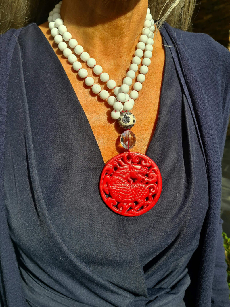 Long necklace of white agates with a red jade medallion and crystal